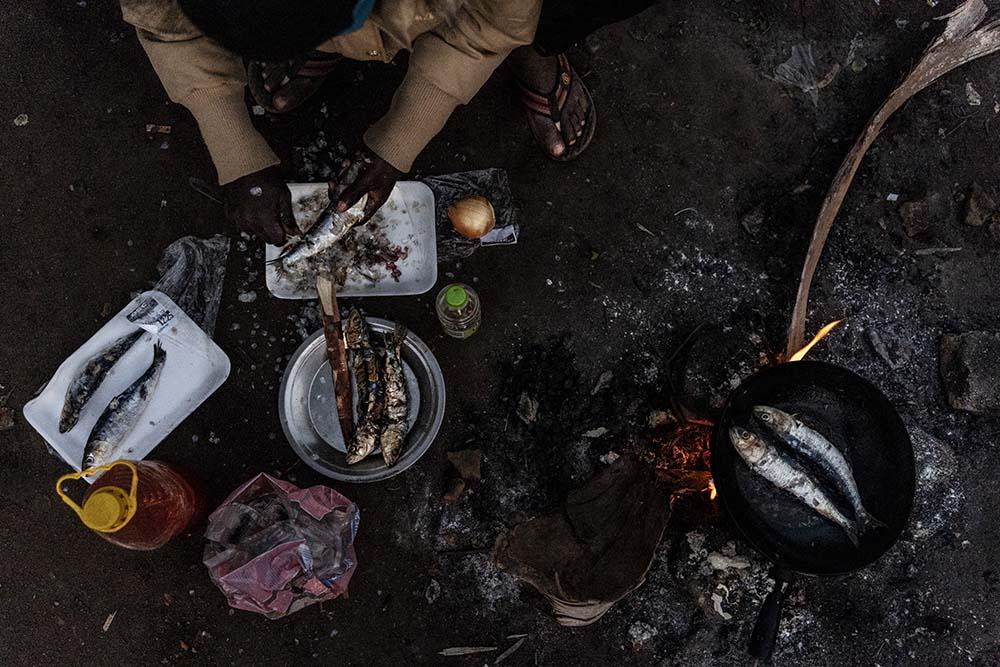 A man prepares Sardines ahead of dinner at a shelter for refugees and vulnerable migrants located in the border town of Musina. A man stands over the only working tap at a shelter for refugees located in Musina, South Africa.