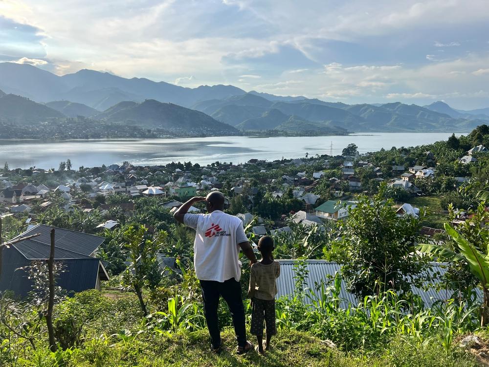 An MSF staff member and a child look at the town of Minova and Lake Kivu from the top of a hill. South Kivu province, eastern DRC