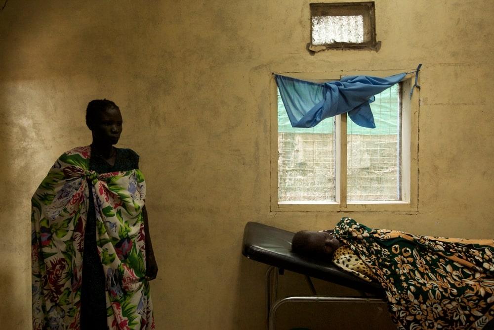 A woman stands over the sickbed of a person suffering from kala azar