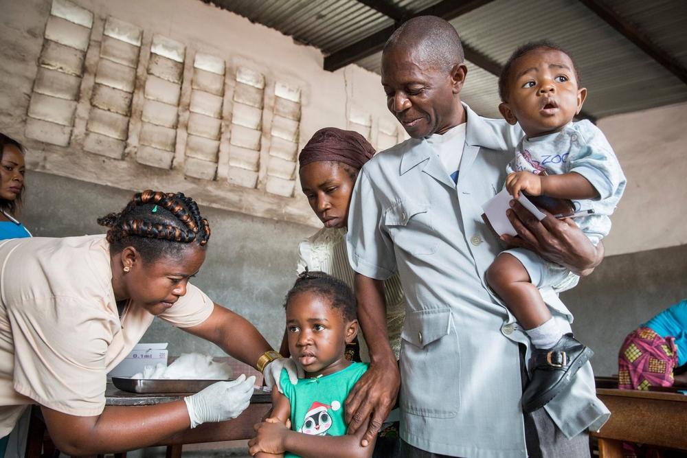 Pasteur Thierry Kasiala goes with his family to a vaccination center in the zone of Mfumu Nkento. He's accompanied by his wife Henriette, his daughter Sidonie (4yrs) and his baby son Emery (9m) and the community worker Bertin. Thierry is a pasteur in the christian church 'Assemblée de Kinshasa'. He has also created an ngo which is helping people who are suffering from malnutrition and HIV/Aids. His church is very popular and has over 3000 members.