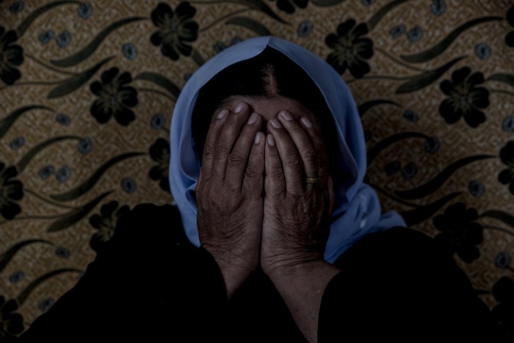 A woman holds her hands over her face.