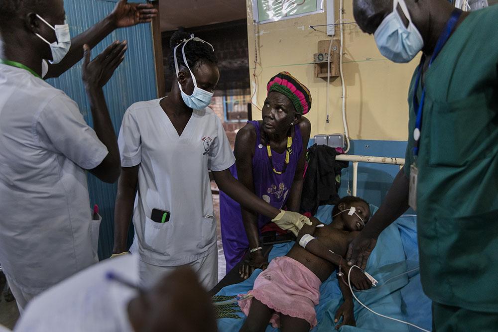 Atong Dut Deng, 8 years old, infected with cerebral malaria. She is being attended to by MSF medical staff in the ICU at MSF supported Aweil State Hospital. She is accompanied by her grandmother Rebecca Achol Atak (age unknown). South Sudan, October 26th, 2021. 