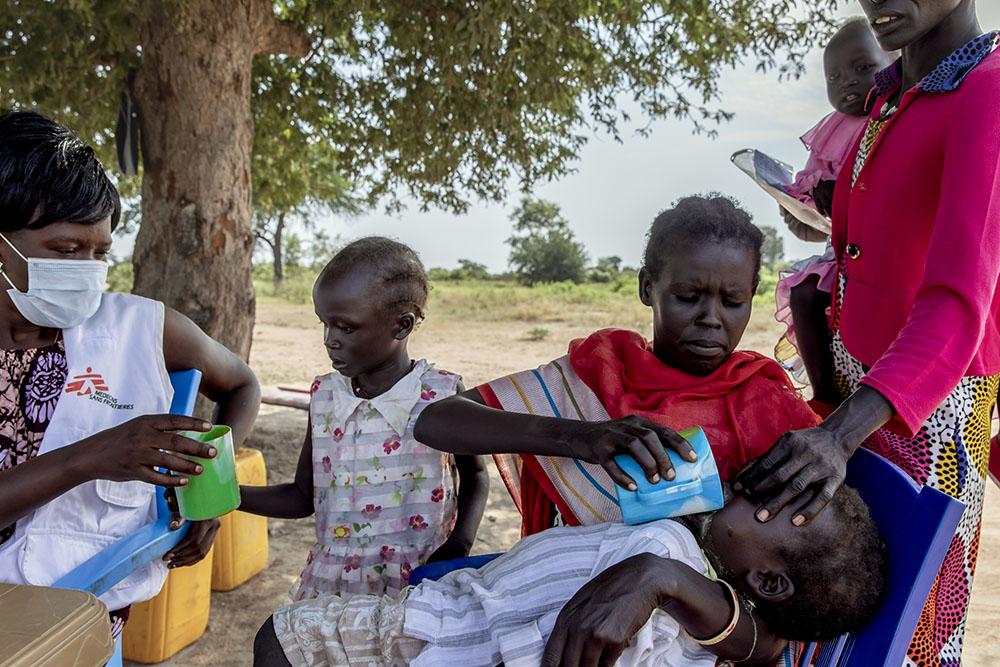 A mother gives SMC medication to her child at a seasonal malaria chemoprevention distribution site in a village in Aweil, South Sudan, October 28th, 2021. 