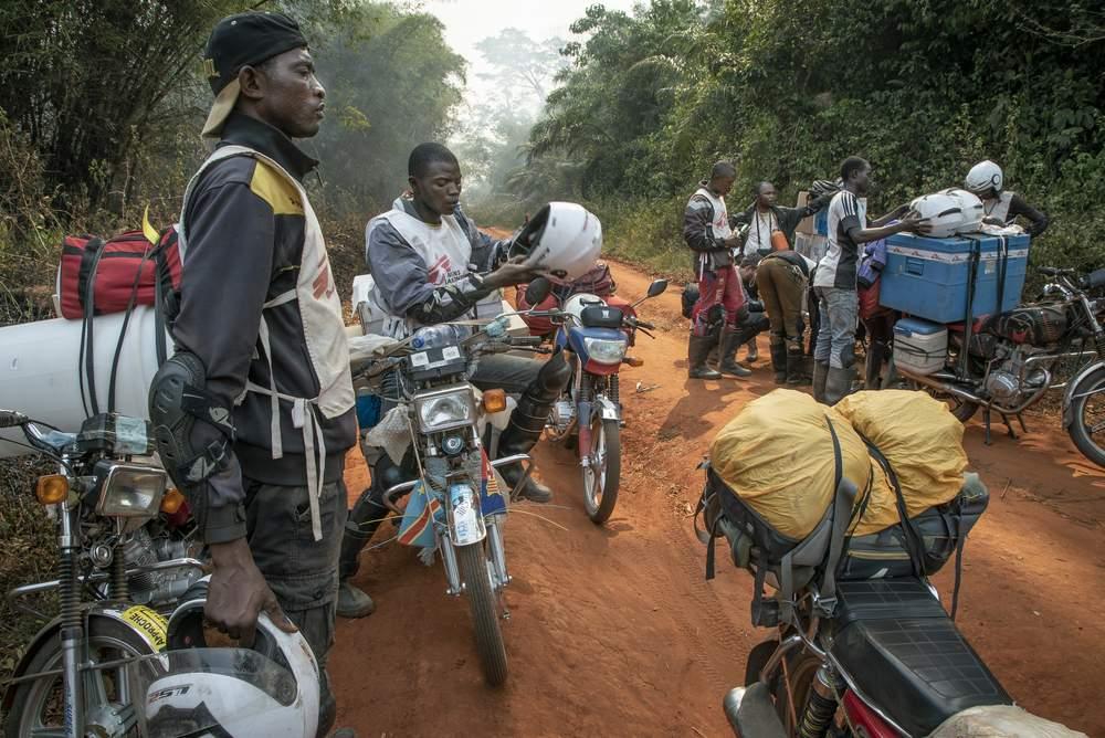 MSF staff members delivering measles vaccine by motorbike to Boso Manzi