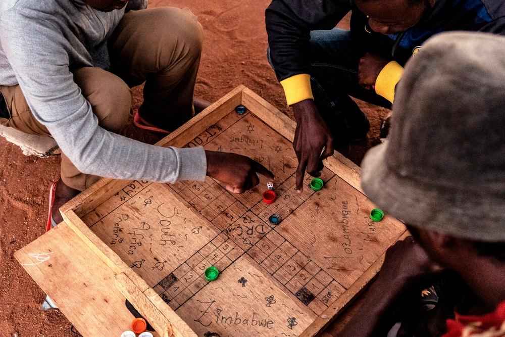 Men staying at a shelter for refugees in Musina, South Africa play a game of "Ludo" on a board with the names of the various countries some of the migrants who have stayed at the camp come from. 