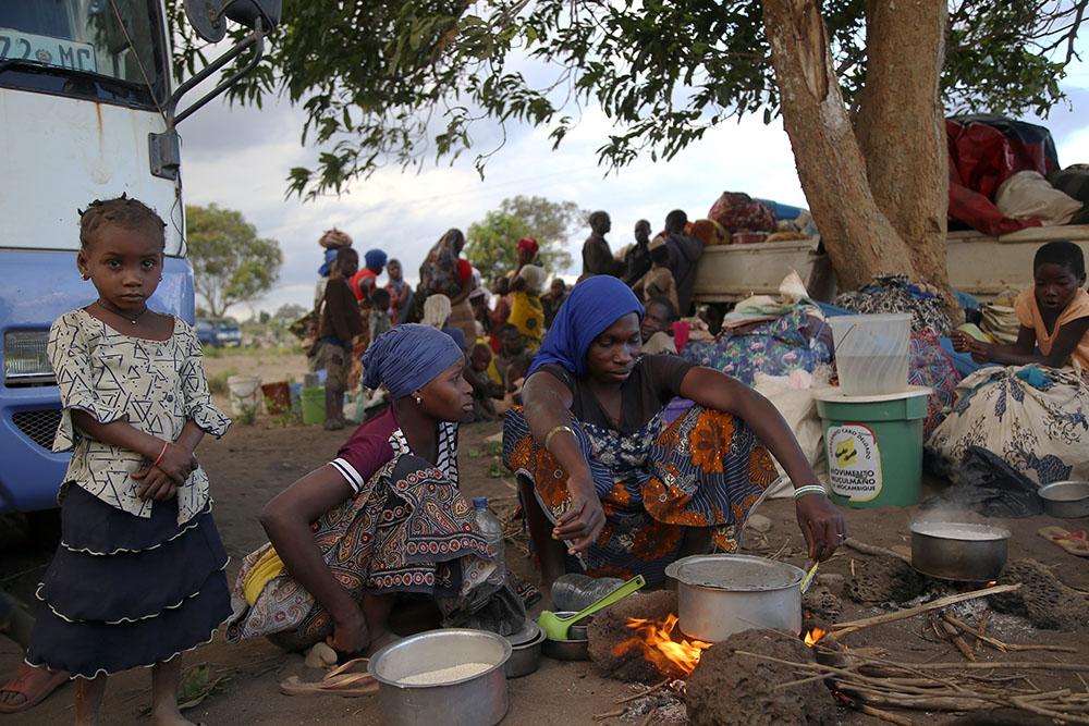 A woman cooks over an open fire, on the outskirts of Mueda, in the northern Mozambican province of Cabo Delgado. Authorities organized nearly 60 trucks to drop hundreds of people in this area on 11 December. People had been stuck on the road for nearly two weeks in some cases while they were attempting to move further to Palma, a coastal town that was attacked earlier this year and where some people have already gradually returned.