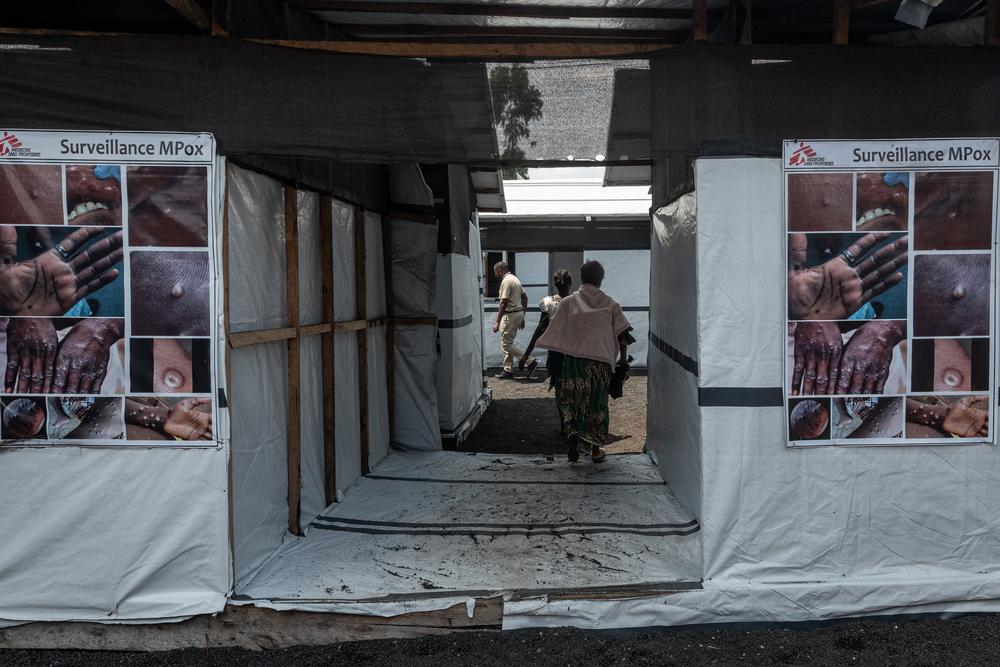 People enter a canvas and wood MSF mobile clinic.