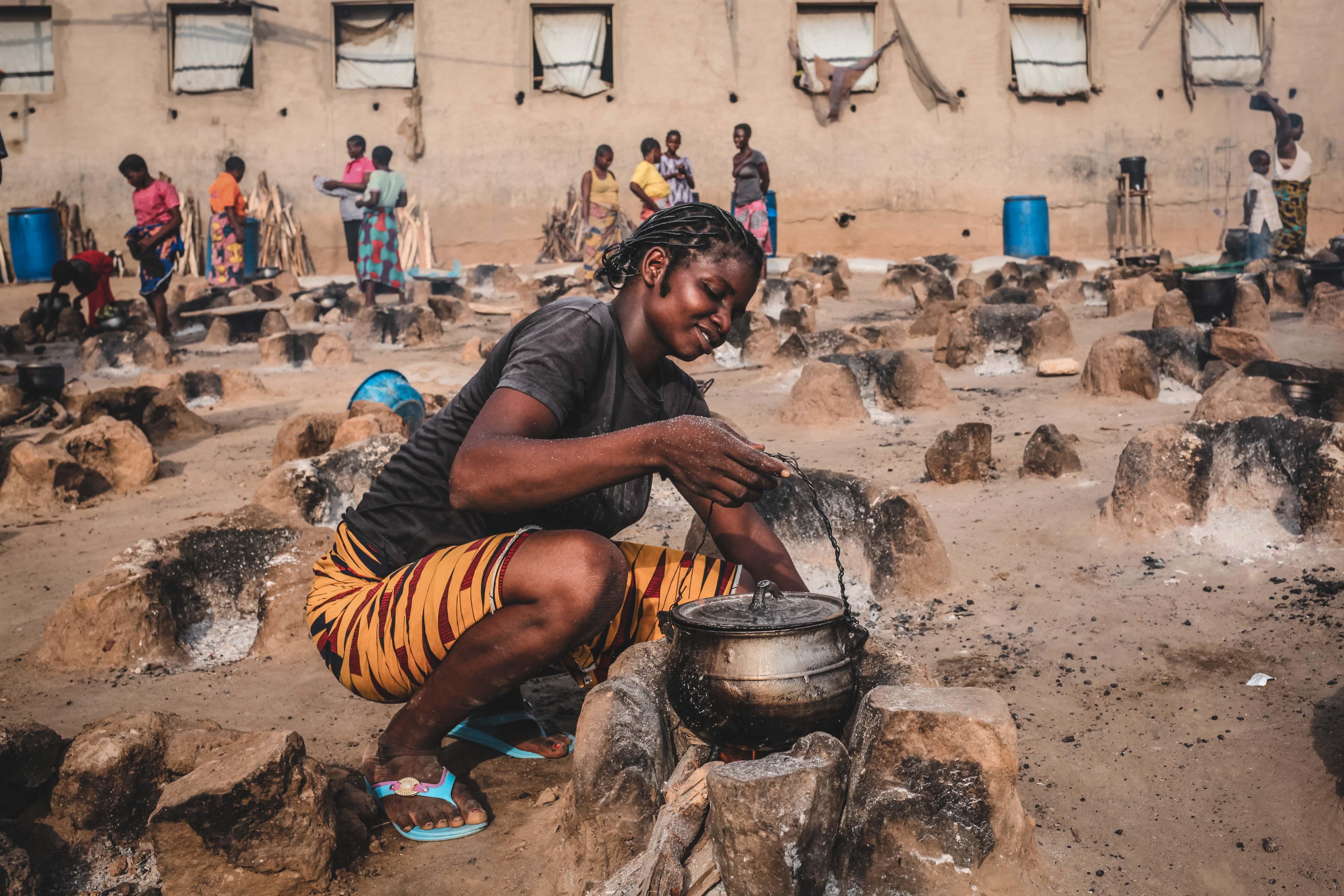 A young woman cooks an evening meal for her family in an open-air cooking area Abagana camp.