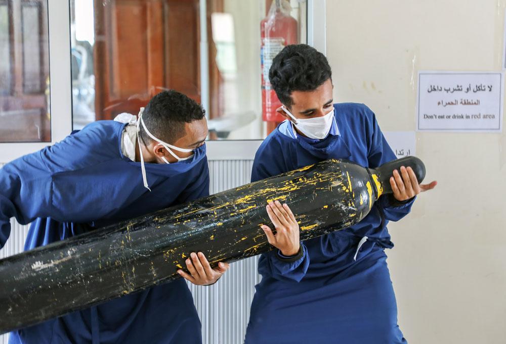 Two MSF staff carrying oxygen tanks