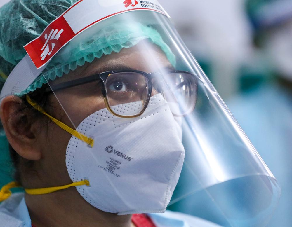 A MSF staff member listening to the protocols being explained wearing PPE 