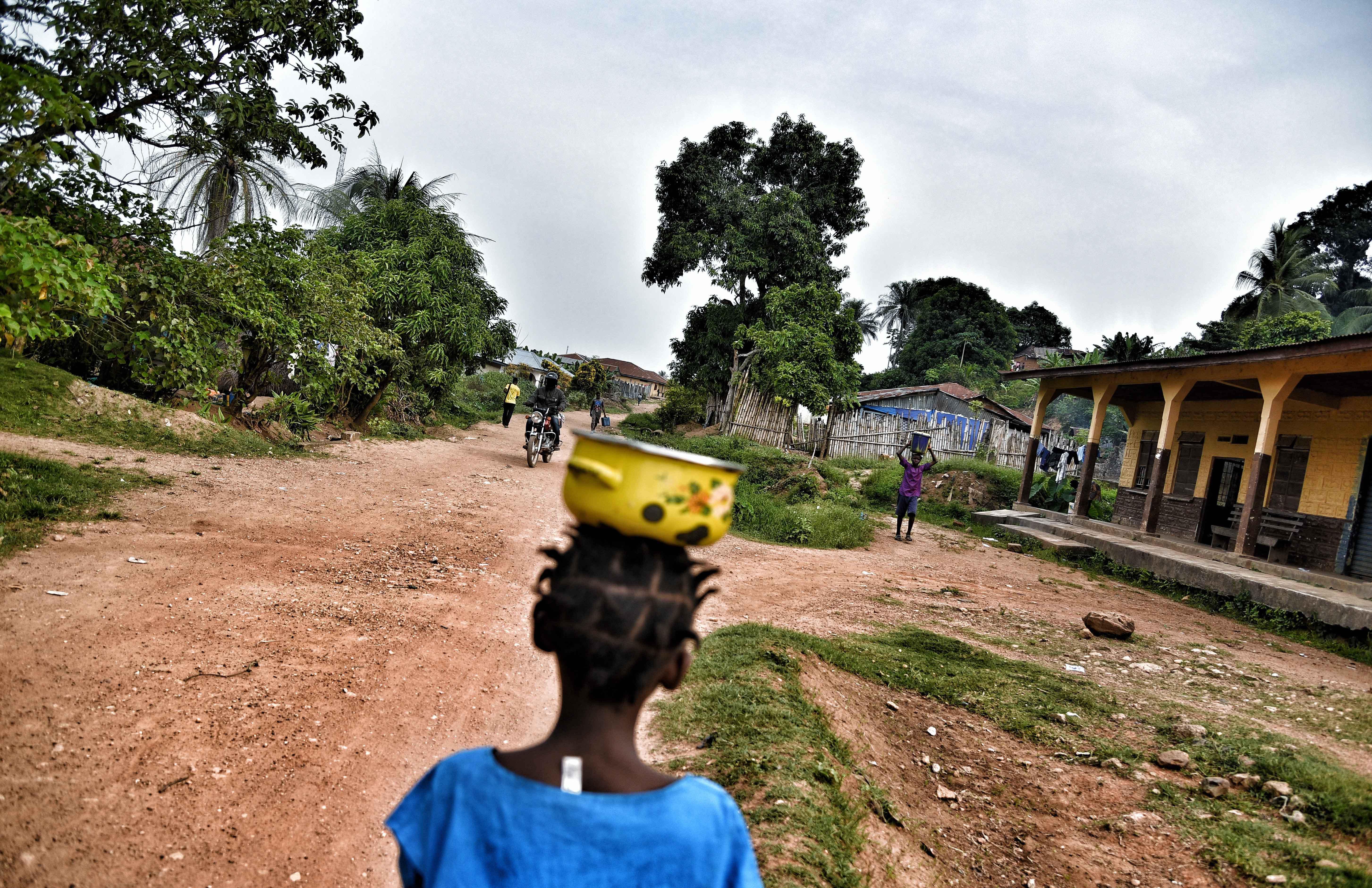 A young girl carrying food as she walks through one of the villages in Gorama Mende chiefdom in eastern Kenema district. 