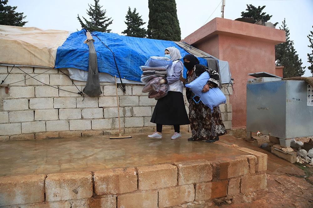 MSF Health Promotion staff are helping a displaced woman by holding the winter kit. 