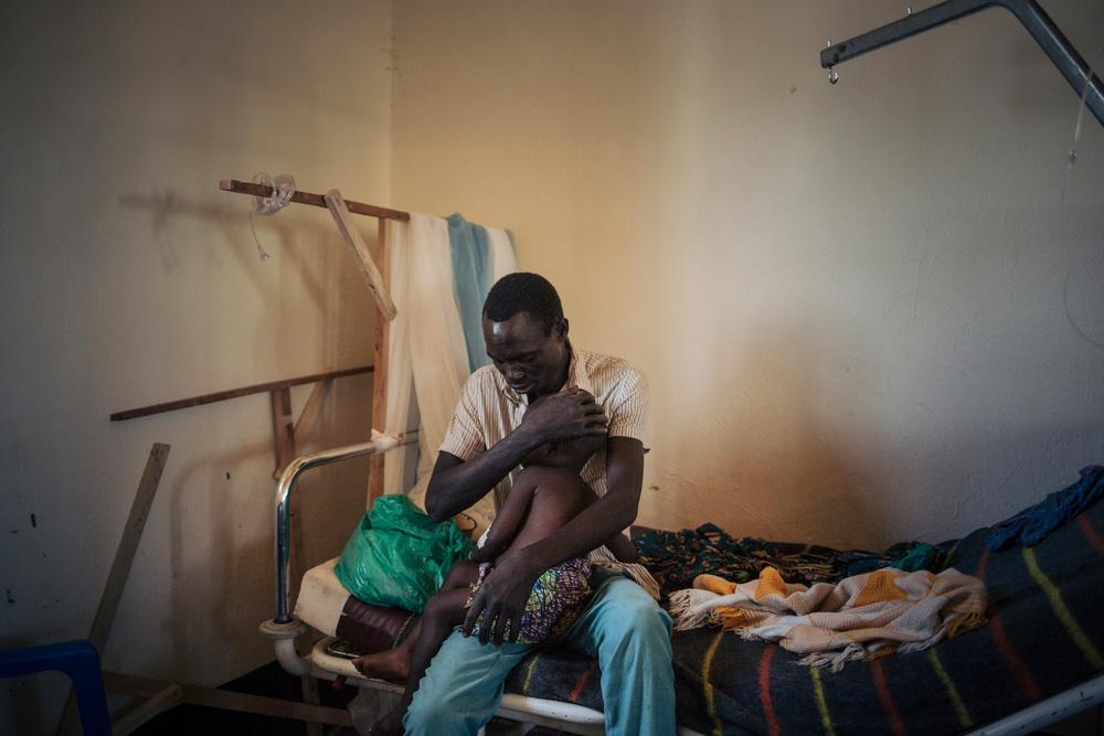 Joseph holds his two-year-old daughter, Bhileru, who is suffering from measles, in the health facility run by MSF