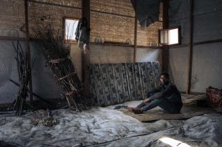 bed, a 20-year-old, single, no children, displaced man, stands with his only belongings in the community shelter where he lives in the informal IDP site of Rugabo Stadium in Rutshuru Centre, in North Kivu province, eastern Democratic Republic of Congo.