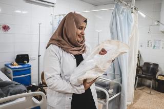 Rahma, Midwife supervisor, is holding a newborn named Rivan. “All the feedback I have received (about the facility) has been positive”, she says.